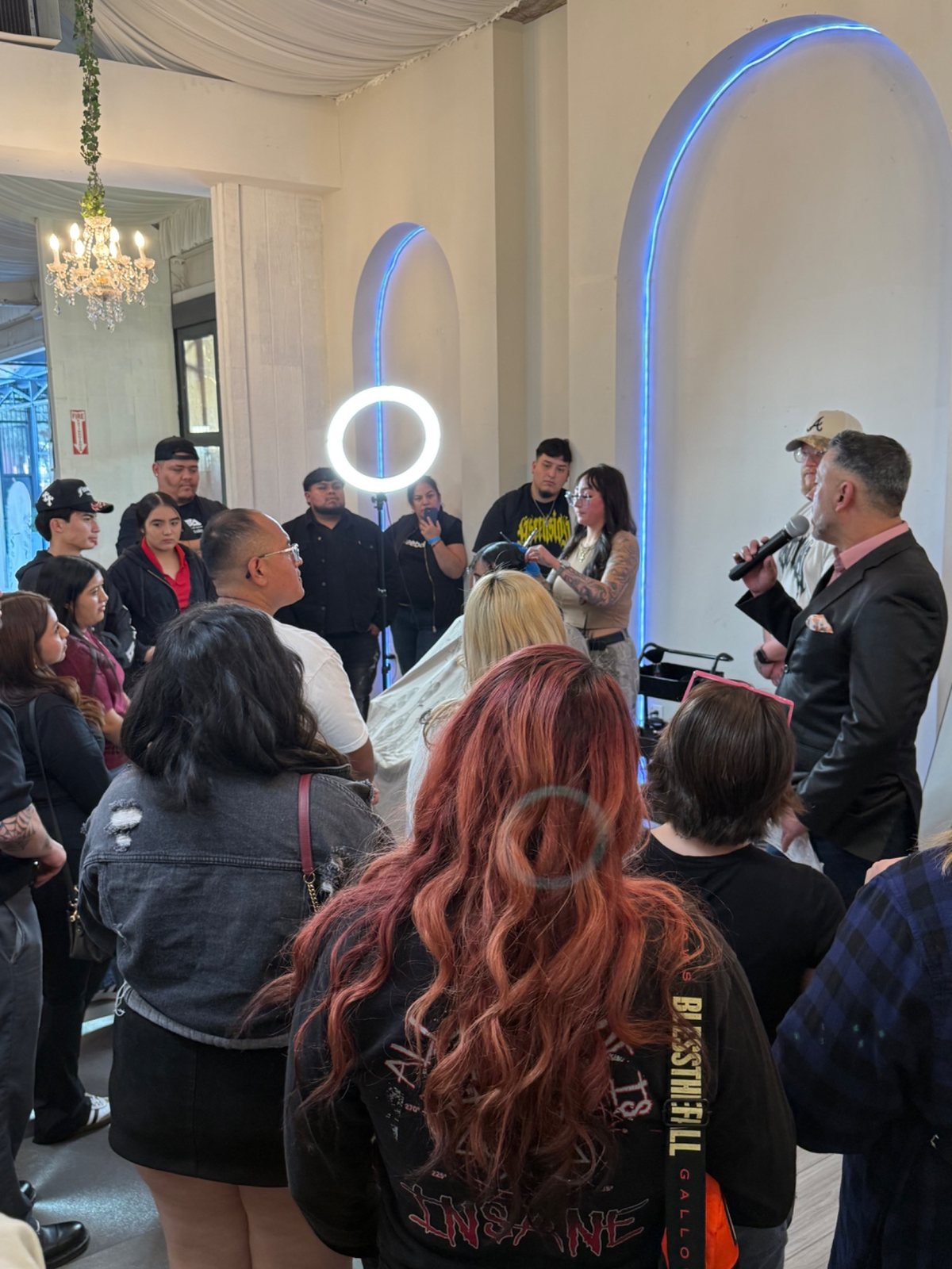 Live barber education event with attendees gathered around a presenter